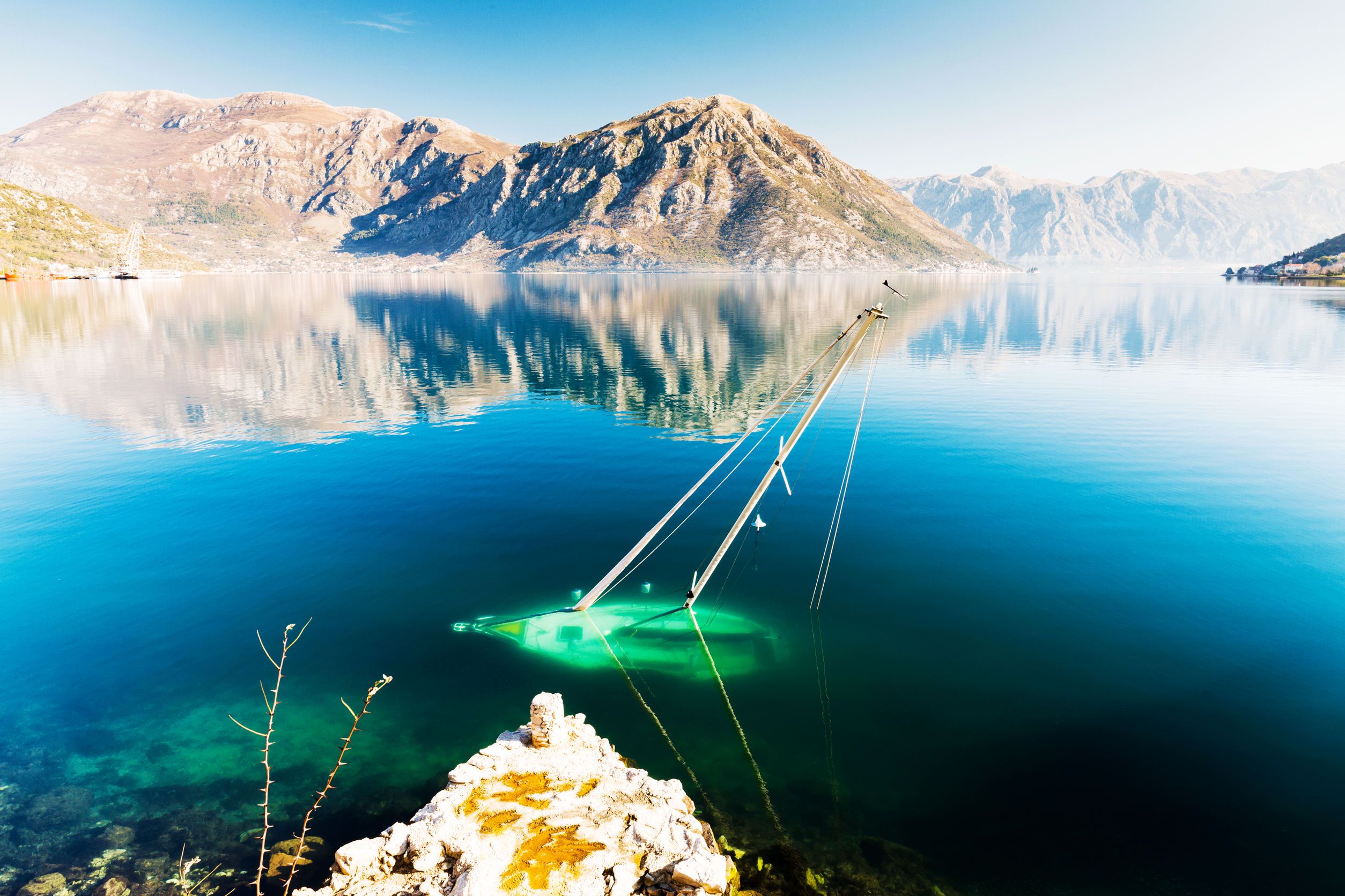 Una barca a vela affondata su un lago con una montagna sullo sfondo.
