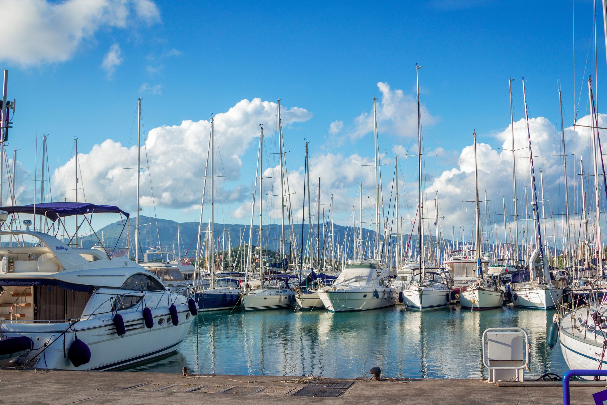 Άποψη της όμορφης μαρίνας του λιμανιού Γουβιών – ήρεμη θάλασσα, λευκά γιοτ και γαλάζιος ουρανός με λευκά σύννεφα