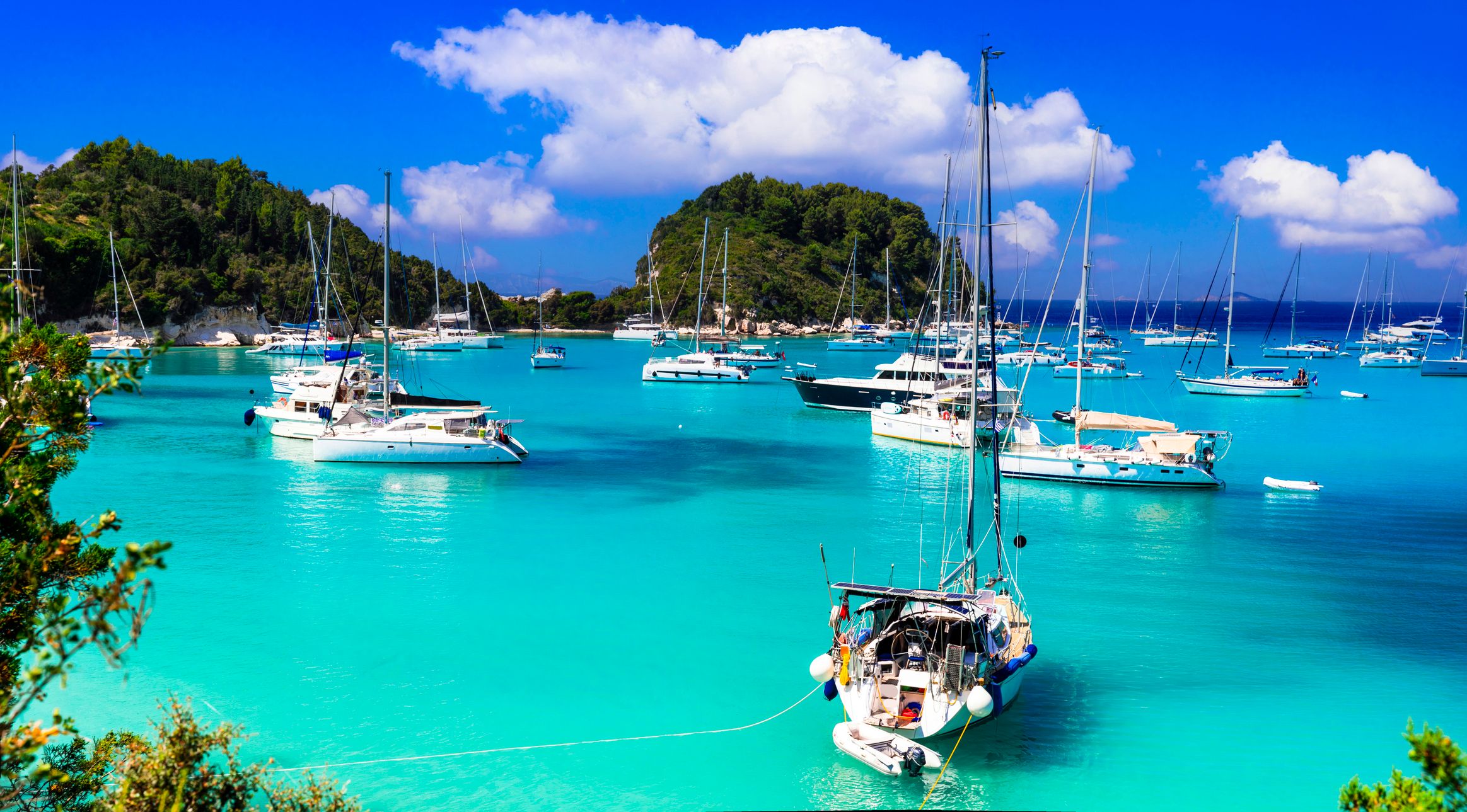 Όμορφο μικρό ελληνικό νησί του Ιονίου Παξοί. θέα της υπέροχης γραφικής παραλίας και του κόλπου Λάκκα με ιστιοπλοϊκά σκάφη. Ταξίδια στην Ελλάδα