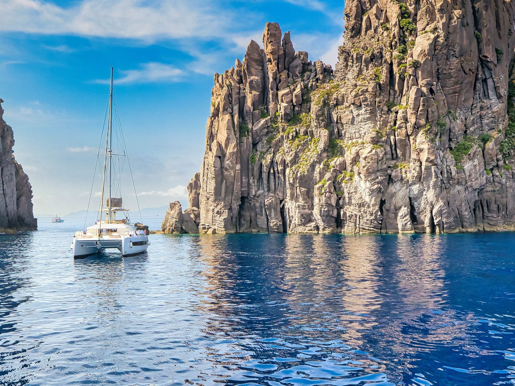 A catamaran sailing near a reef in the Aeolian Islands