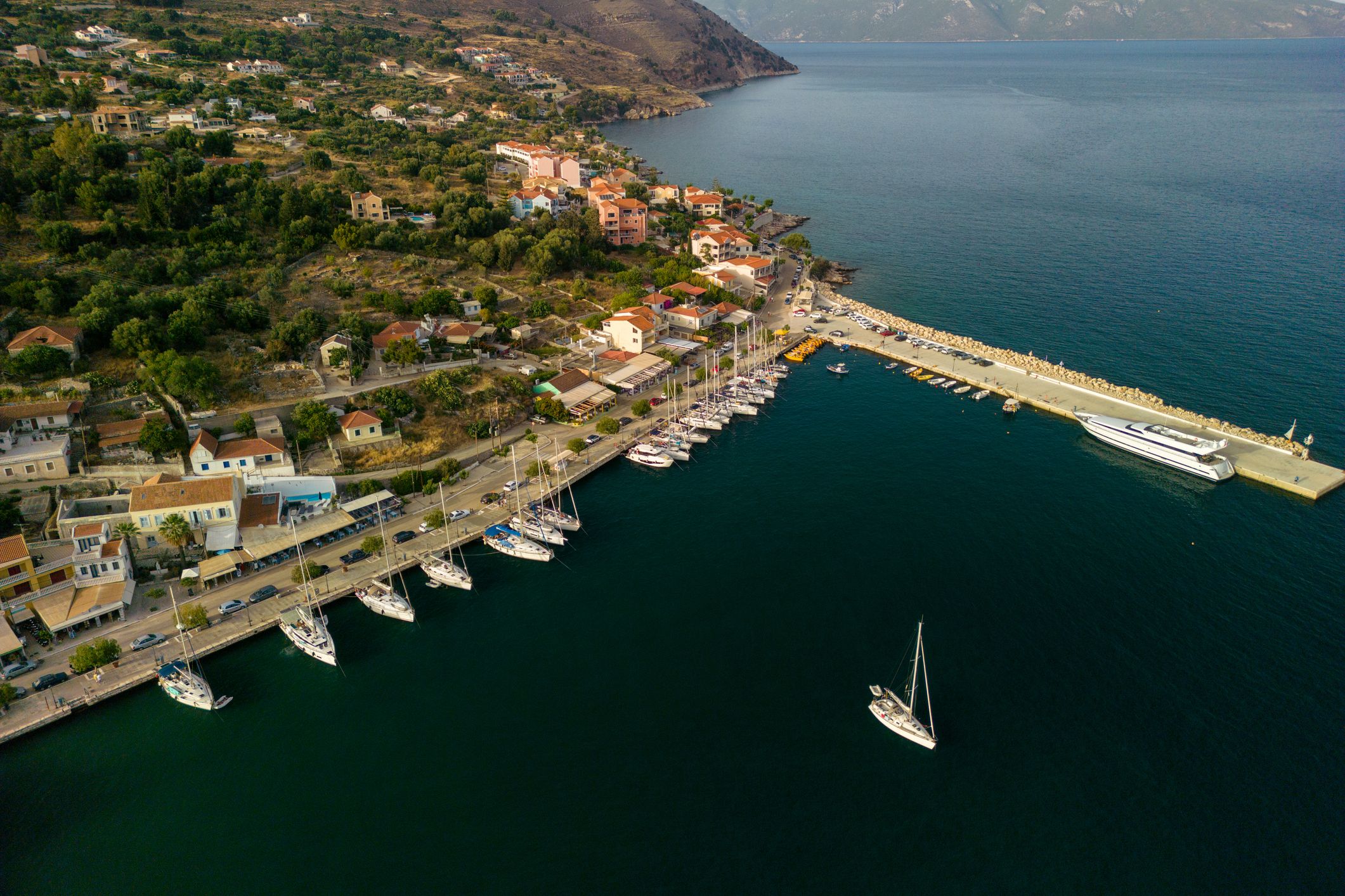 Sailboats and yachts docked in a bay of Agia Efimia marina at sunset, Kefalonia island, Greece.