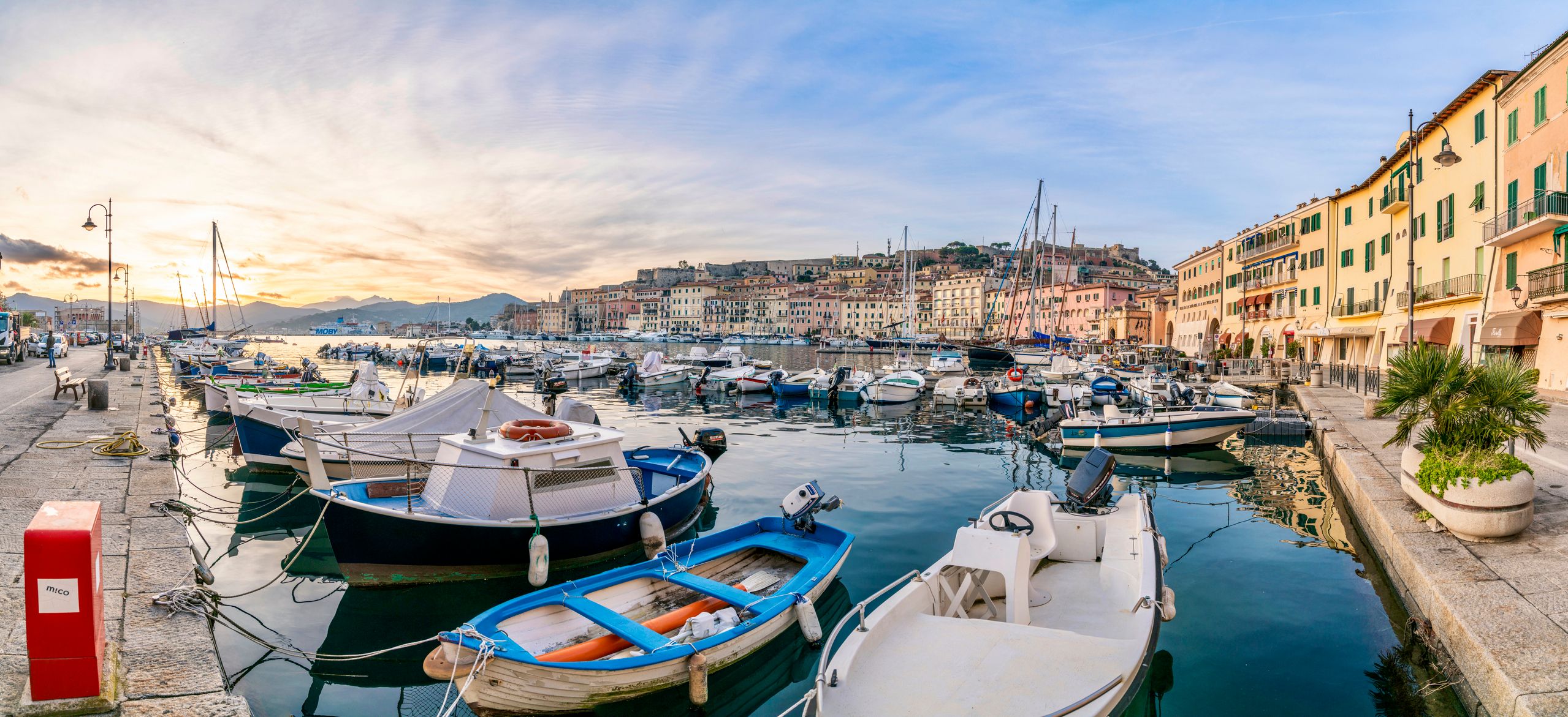 Beautiful Mediterranean Village Harbor with sailing and fishing boats, Portoferraio in Elba, Italy. Sunlight in the back and shiny water.