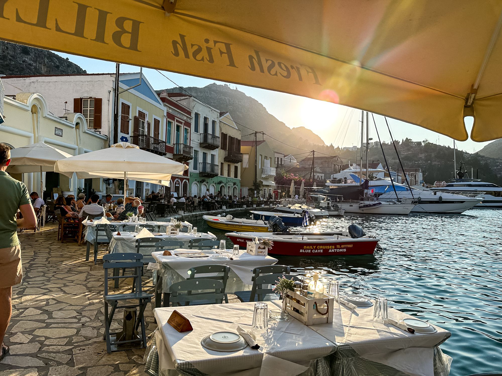 Traditional Greek taverna by the sea in Kastellorizo island. People sitting at a traditional Greek taverna located by the sea in Kastellorizo, Greece