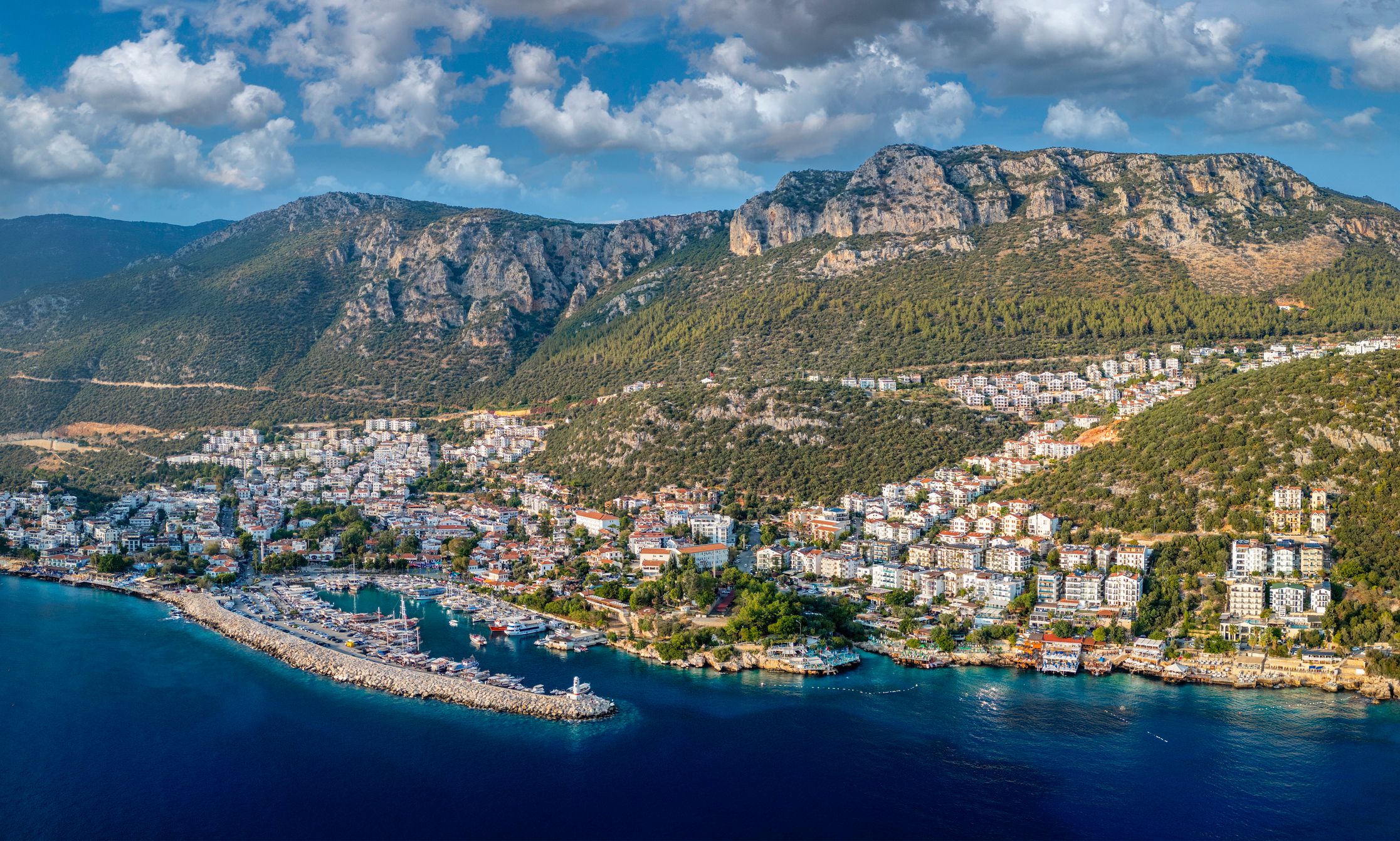 Aerial view of kas, a charming coastal town in antalya, turkey, showcasing its picturesque marina, white-washed buildings, and the stunning taurus mountains