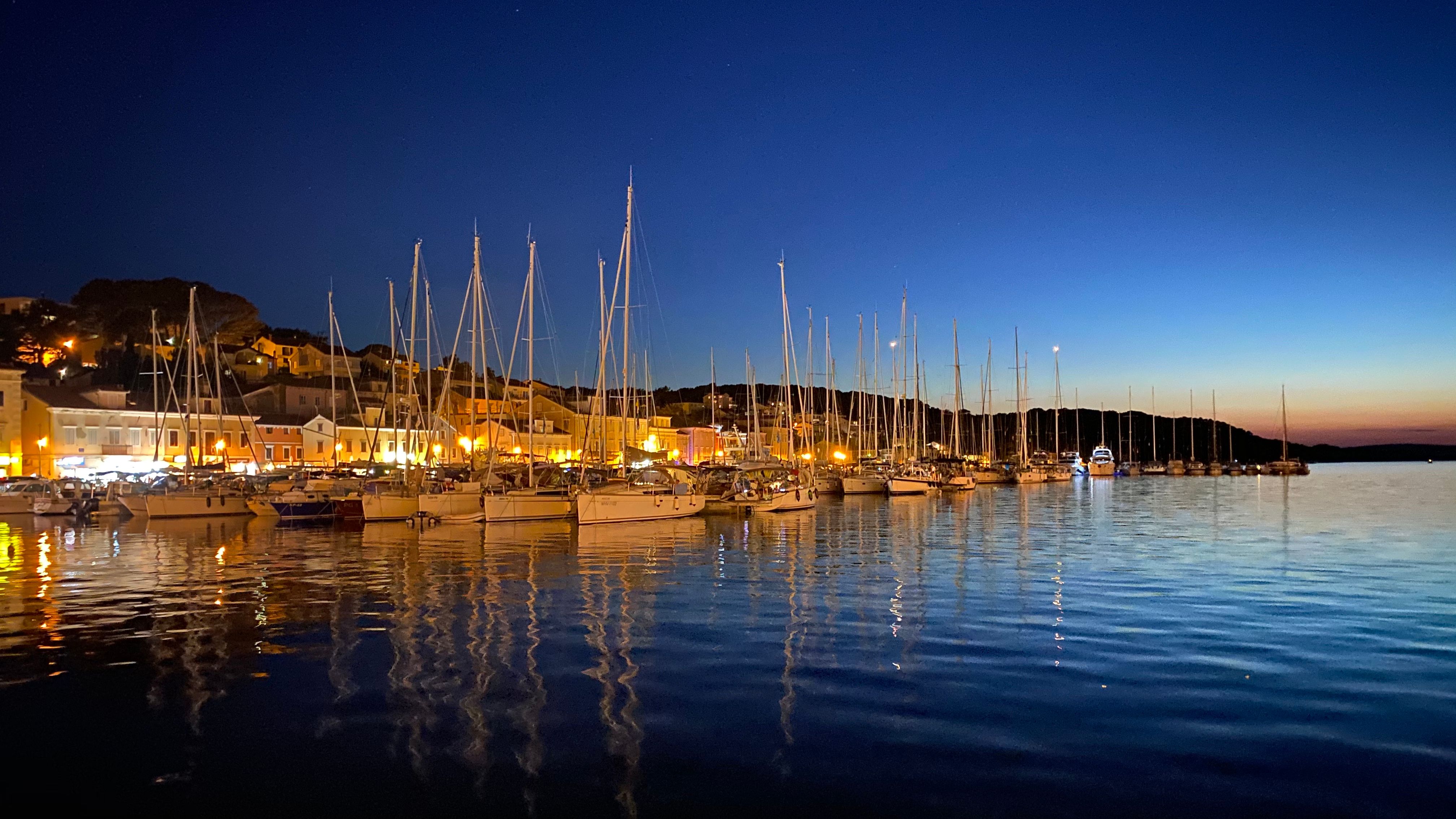 Noć u Marini Mali Lošinj, Hrvatska, s jedrilicama usidrenim ispred slikovitog sela