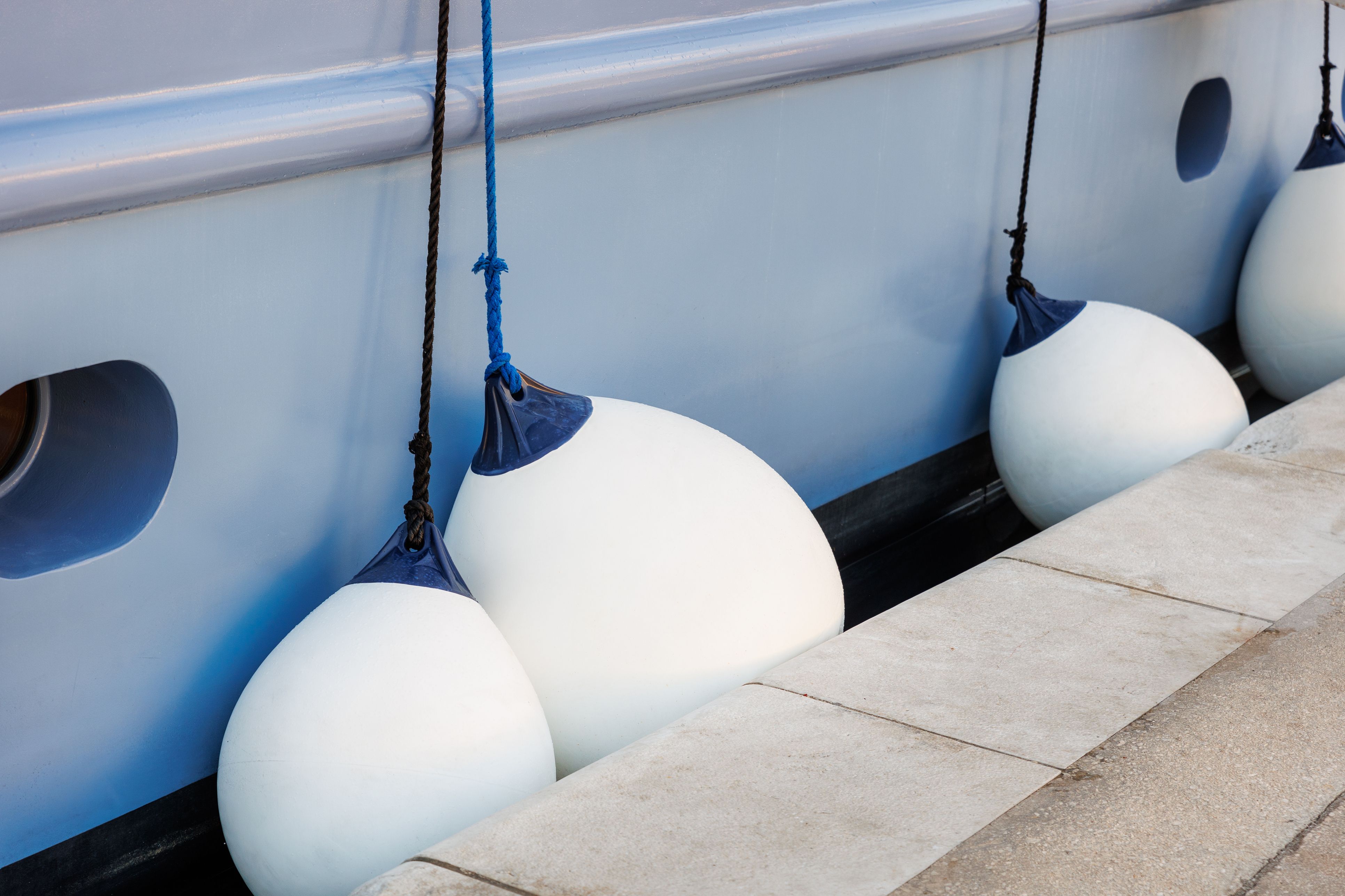 Nahaufnahme, Detailansicht einer großen Luxus-Kreuzfahrtyacht, die im Hafen der kroatischen Bucht vor Anker liegt, an der Anlegestelle mit Plastikfendern bei strahlendem Sonnenschein im Sommer bei Sonnenuntergang und Sonnenaufgang. Bootscharterservice.