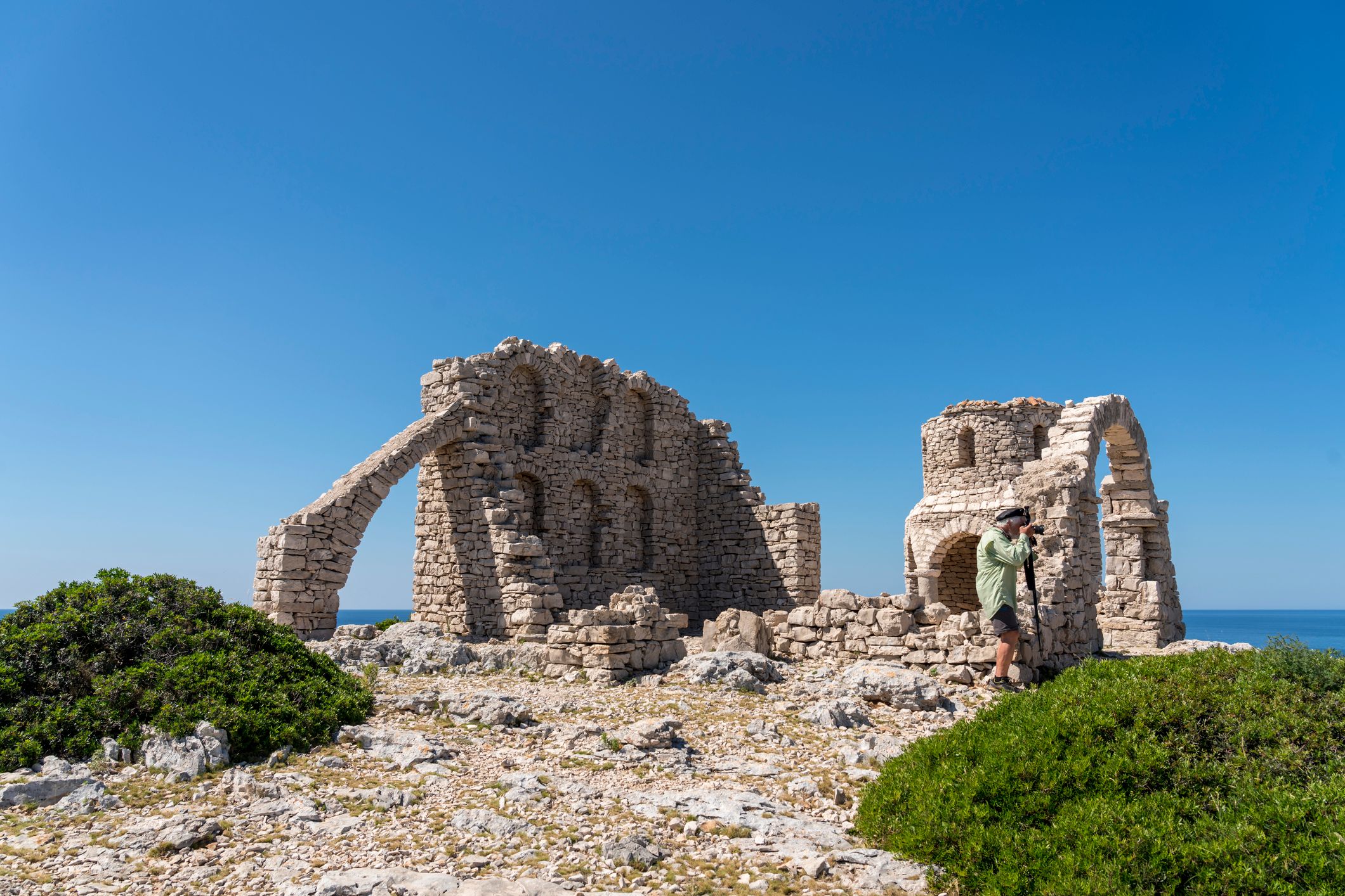 On small Mana island at the door of Kornati islands there are forgotten movie sets from 1959. Senior men standing on top of the island and photographing.