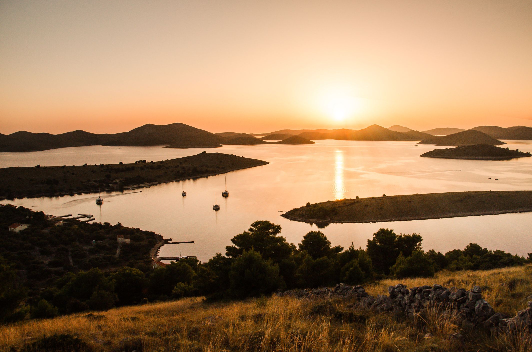Beautiful sunset over the famous Kornati national park in Croatia, Europe, view from the top of the Zut island, sailboats on the sea, calm evening
